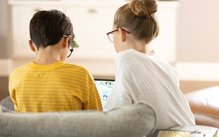 Two kids with glasses looking at a computer