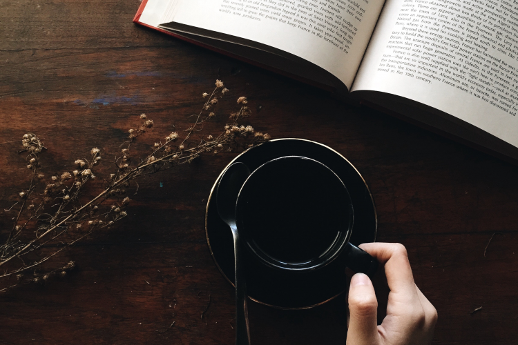 Person drinking coffee with book