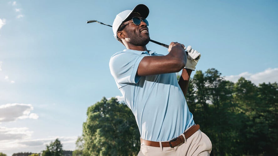 Person wearing sunglasses swinging a golf club