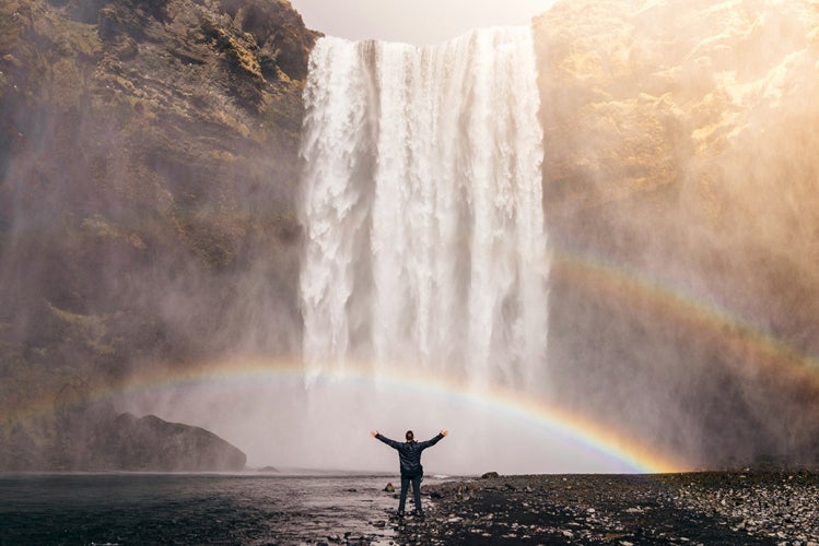 Person looking at a waterfall with rainbows