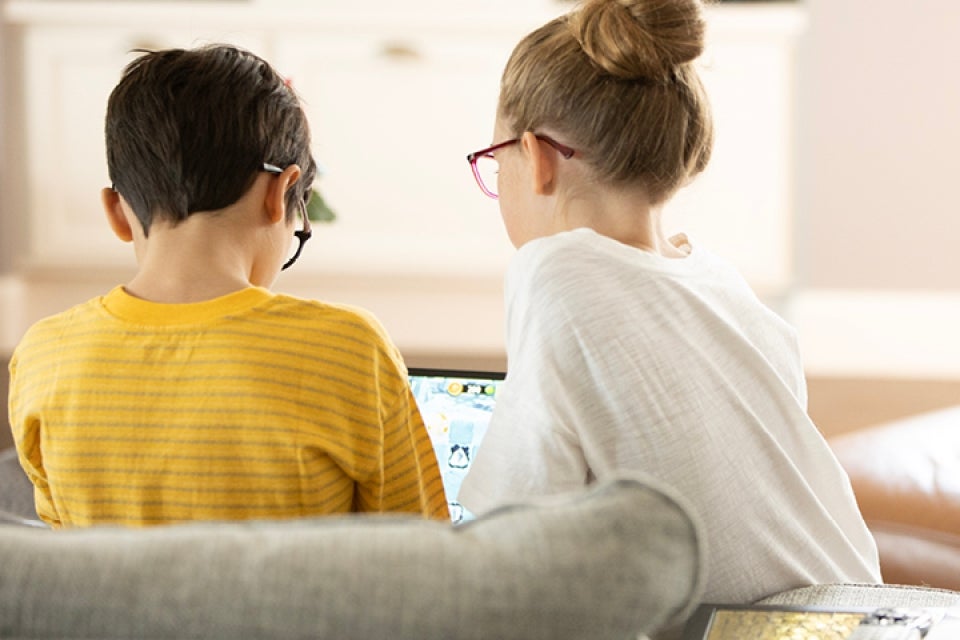 Two kids with glasses looking at a computer