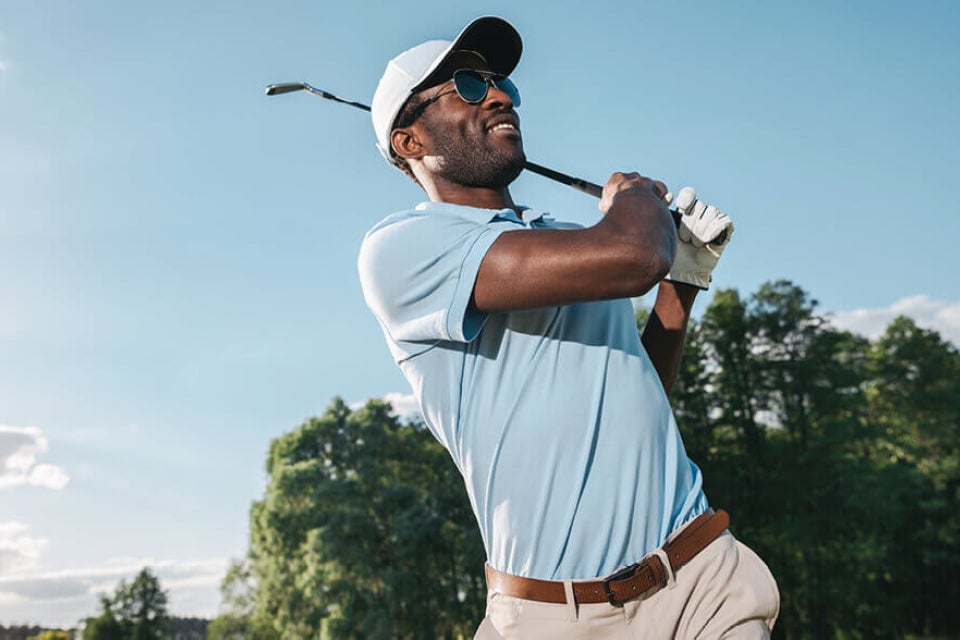 Person wearing sunglasses swinging a golf club