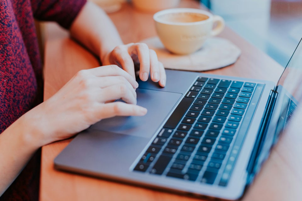 Person using notebook while look at laptop screen