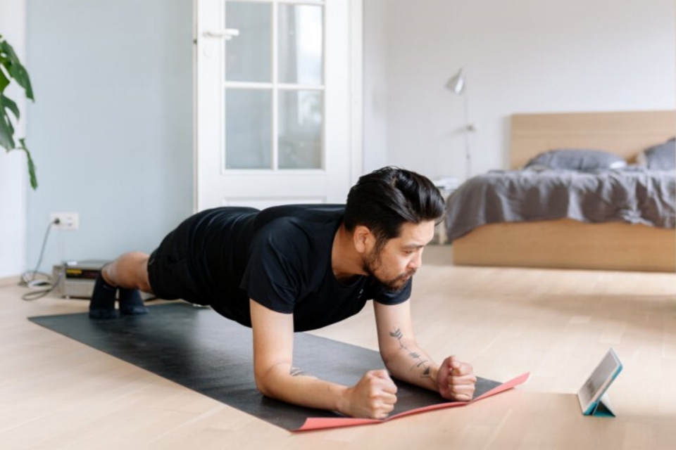 Man doing yoga at home watching a video