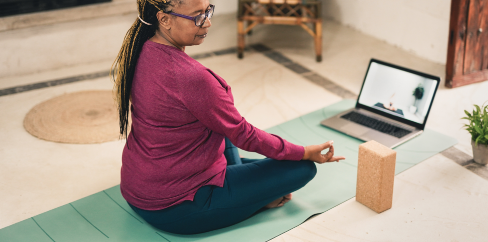 Woman doing yoga virtually with laptop