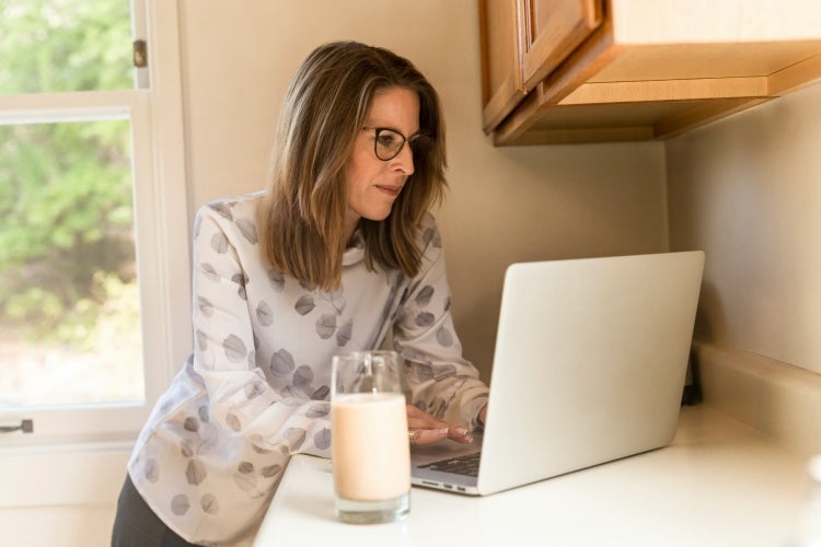 Person typing on a laptop in a kitchen nook