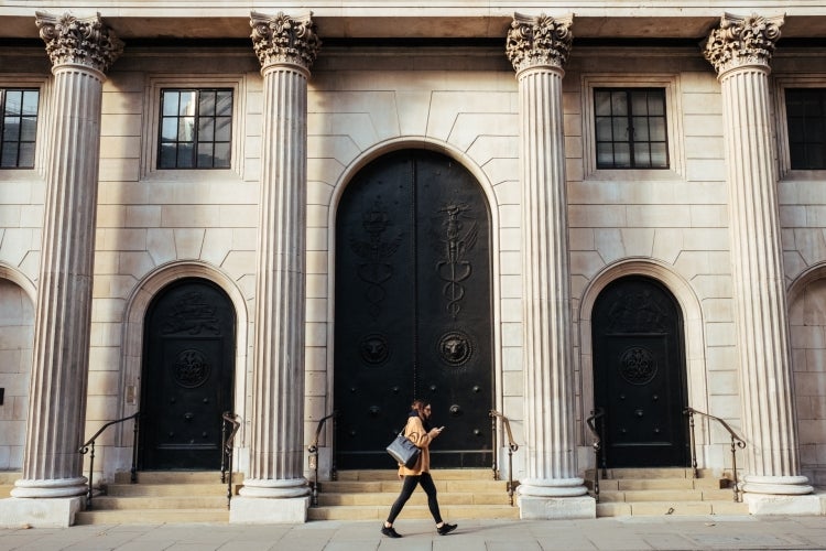Person waking in front of a building with large columns